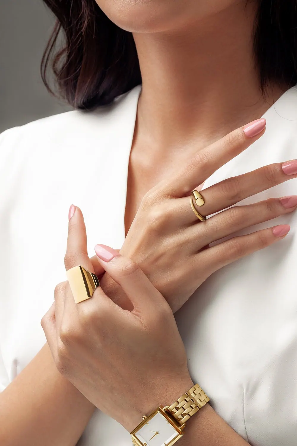 דוגמנית מצולמת עכ תכשיטי זהב יוקרתיים ושעון זהב לובשת חולצה לבנה פריסטינית בצילום ייחודי לדגמי תכשיטים