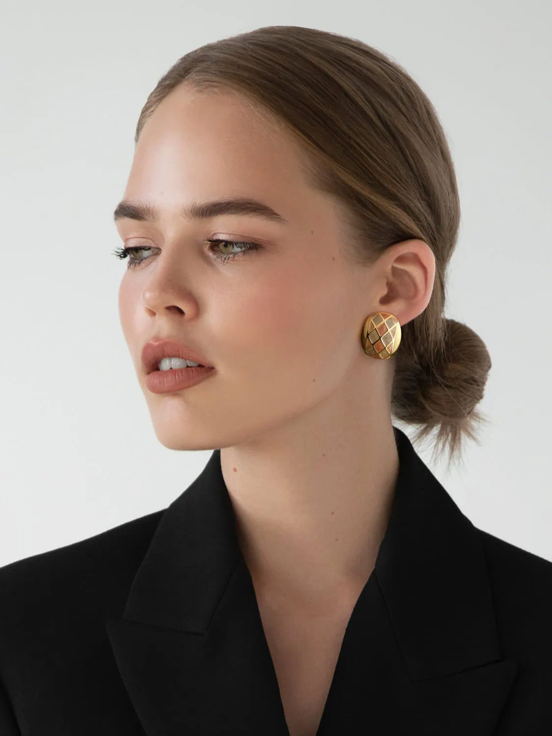 פורטרט מהפנט של דוגמנית עונדת עגיל גדול מזהב בסגנון וינטג' דוגמה לצילום תכשיטים מקצועי שמתמקד בדגמי יוקרה