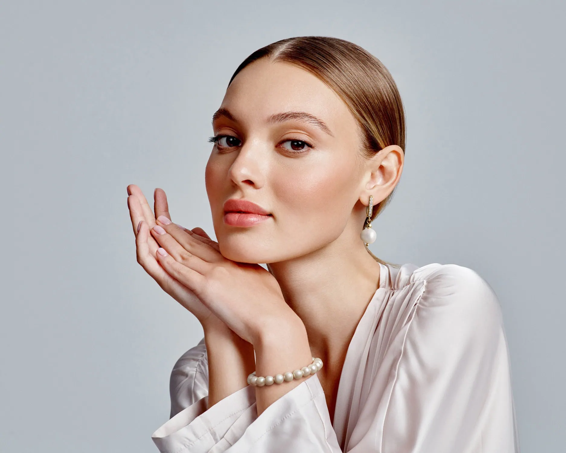 פורטרט רומנטי של נערה עונדת עגילי פנינה וצמיד משקף את הדיוק של צלם תכשיטים