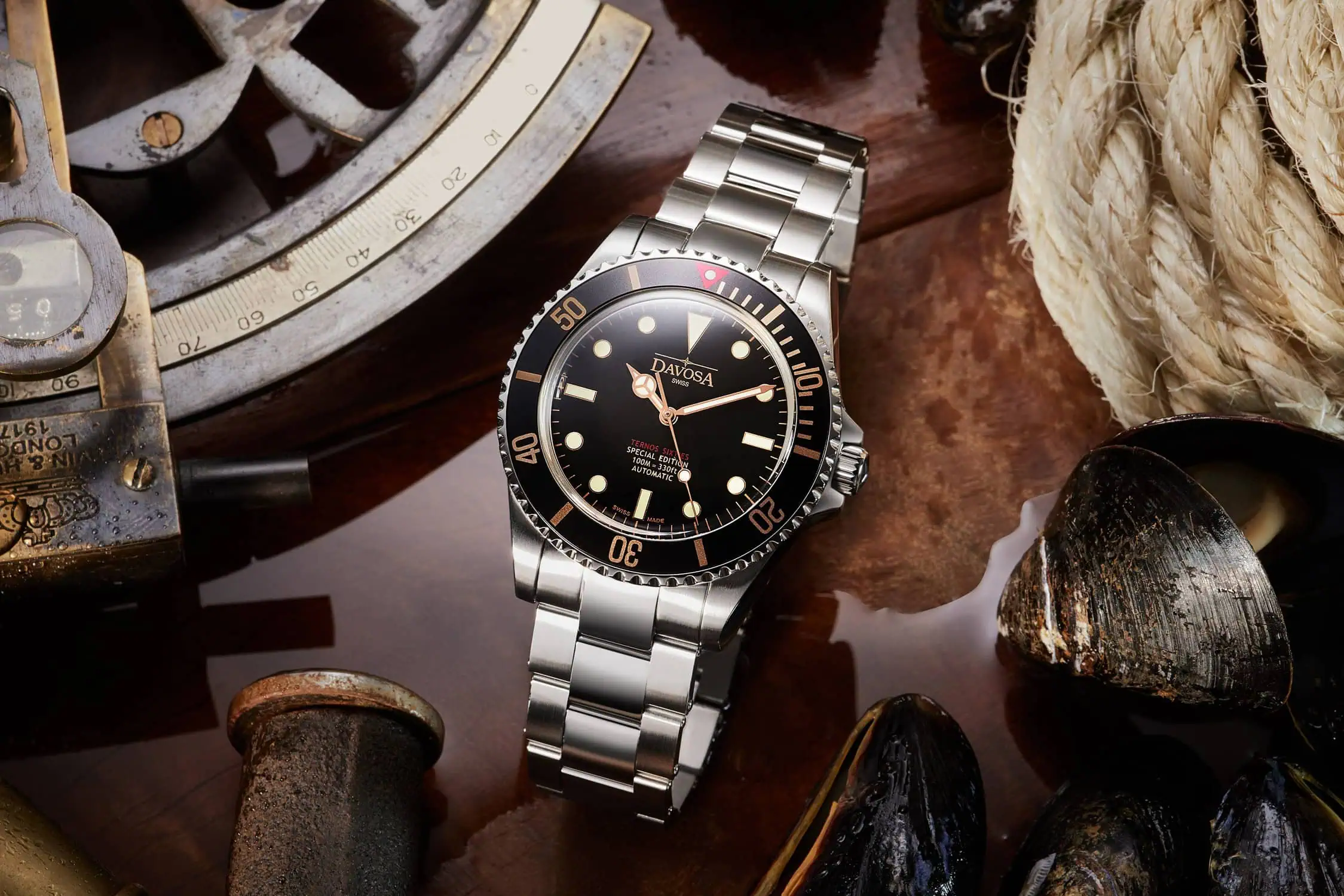 שעון כסף מוקף במים לצד צדפות ופריטים ימיים יוצר אווירה ימית קסומה בצילום שעונים לפרסום